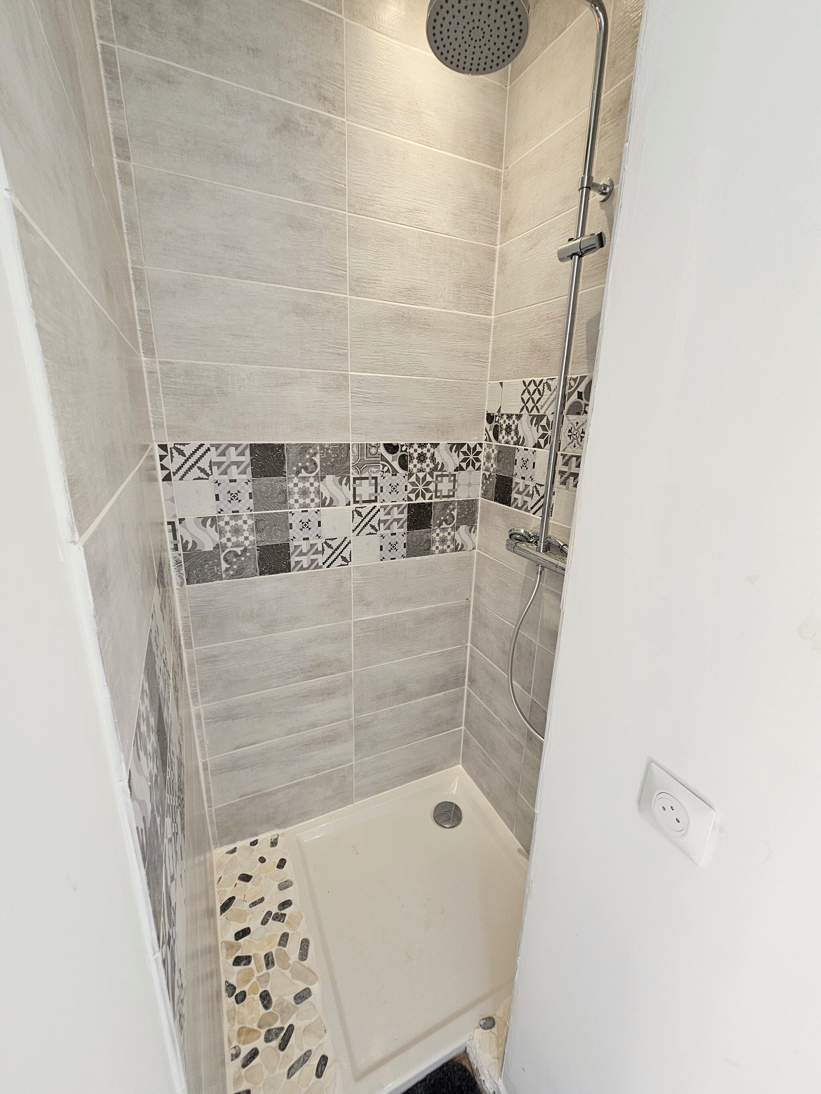 A shower with a rain showerhead, a handheld showerhead, and a handheld showerhead.