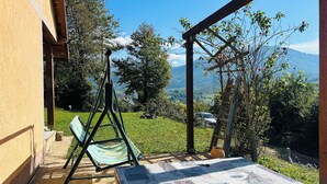 Un patio con una mesa cubierta con un mantel estampado, una hamaca y un columpio de madera.