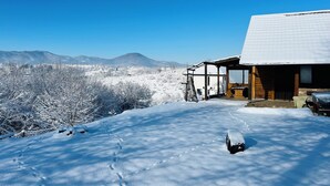 Un paisaje nevado con una cabaña de madera y un cielo azul despejado.