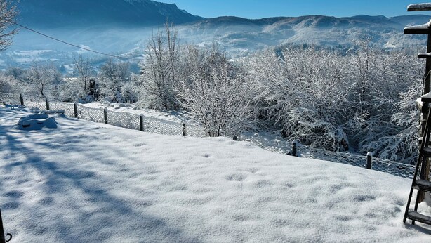 Paisaje nevado con valla de madera y escalera de metal.