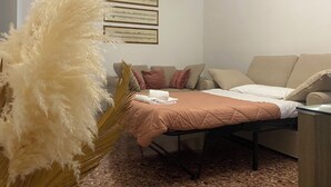 Een moderne slaapkamer met een bed, een bank en een grote sierplant.