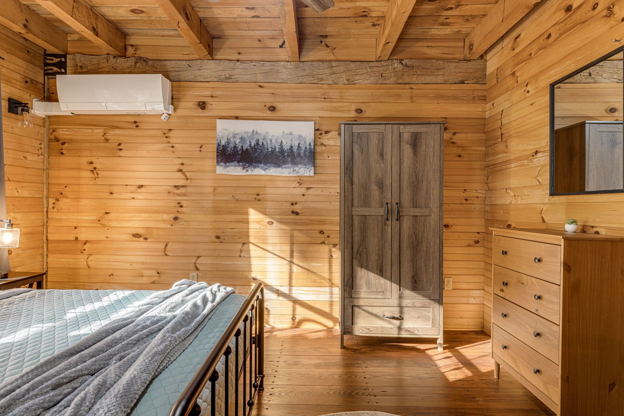 Une chambre dans une cabane en bois, avec un lit, une commode et une armoire.