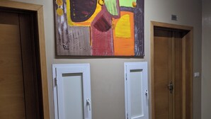 Un couloir avec deux portes, une œuvre d’art accrochée au mur et un sol en marbre.
