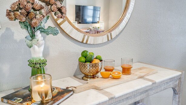 A marble countertop with a glass candle holder, a bowl of fruits, and a cutting board. - Darling Fort Worth Getaway! Located near The Stockyards,Downtown & TCU (Westworth Village)