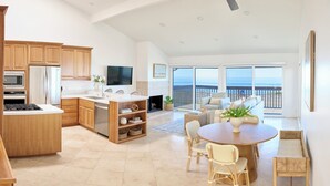 A spacious kitchen with wooden cabinets, a central island, and a dining area with wicker chairs.