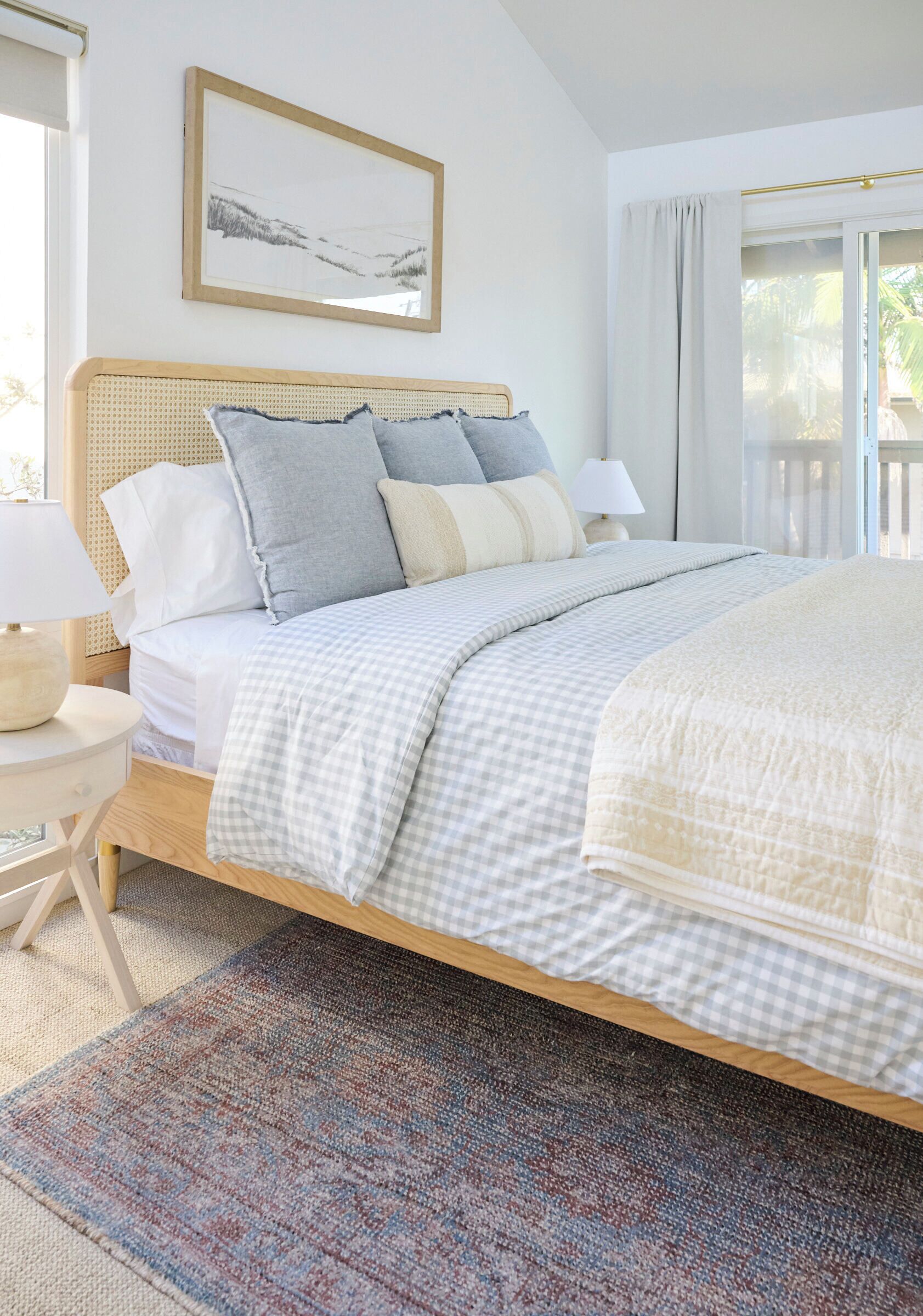A neatly made bed with a checkered bedspread, a bedside lamp, and a framed picture on the wall.