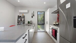A modern kitchen with a central island, stainless steel appliances, and a window with blinds.