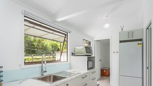 A modern kitchen with a large window, stainless steel sink, and built-in appliances. - Rewa Rewa Retreat - Tairua Holiday Home (Tairua)