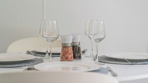 A table set for two with wine glasses, salt and pepper shakers, and a white tablecloth. - Rewa Rewa Retreat - Tairua Holiday Home (Tairua)