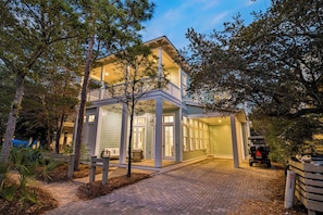 A two-story house with a covered porch, a driveway, and a parked vehicle.