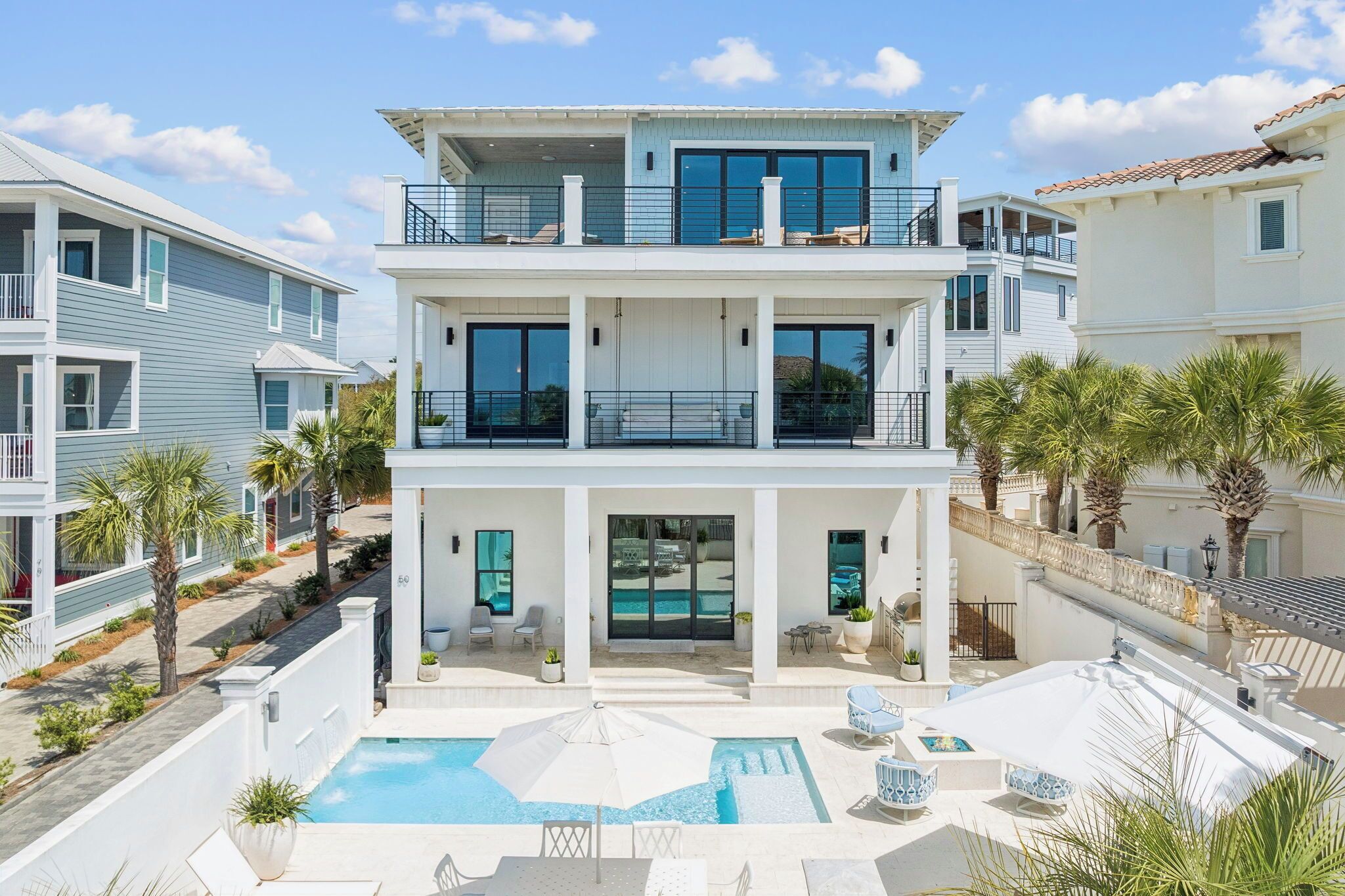 A multi-story residential building with balconies, a swimming pool, and a landscaped patio area.