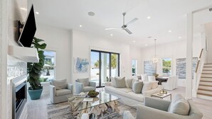 A modern living room with a fireplace, sofa, coffee table, and a large plant. - It's About Time|Unobstructed Gulf Views|Private Pool|Gated Community (Seacrest)