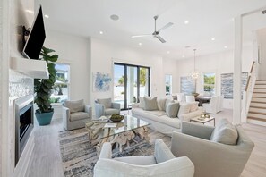A modern living room with a fireplace, sofa, coffee table, and a large plant.