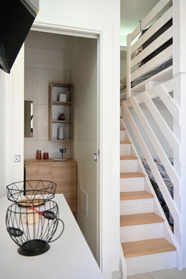 Un intérieur moderne avec un escalier, un mur blanc et un meuble en bois doté d’étagères.