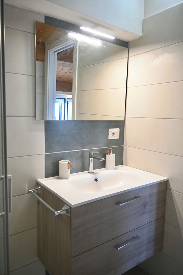 Une salle de bain avec un lavabo blanc, un meuble-lavabo en bois et un miroir au-dessus du lavabo.