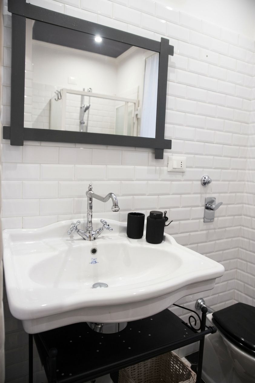 A bathroom with a white sink, black faucet, and a mirror above it.
