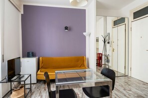 A compact living space with a sofa, a small table, a television, and a refrigerator.