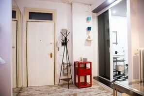 A hallway with a white door, a red side table, and a floor lamp.