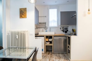 A compact kitchen with a built-in dishwasher, a window for natural light, and a radiator.