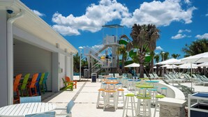 An outdoor pool area with lounge chairs, a water slide, and a covered seating area. - Modern Paradise at Windsor Cay, pool and Game Room (Clermont)