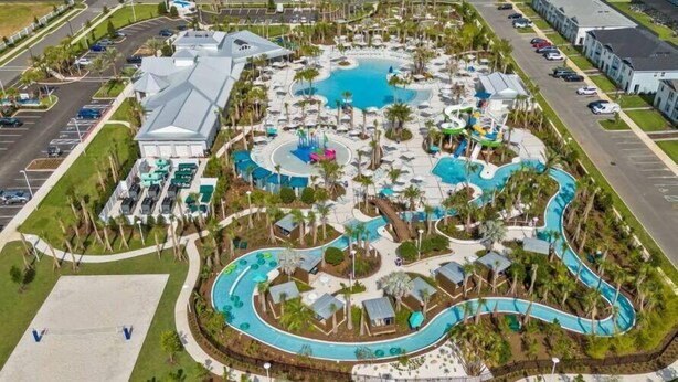 An aerial view of a resort with multiple swimming pools, palm trees, and a parking lot. - Modern Paradise at Windsor Cay, pool and Game Room (Clermont)