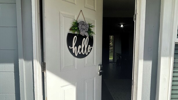A white door with a 'hello' sign and a hanging decoration. - Rayben Residence - Centrally Located (Jacksonville)