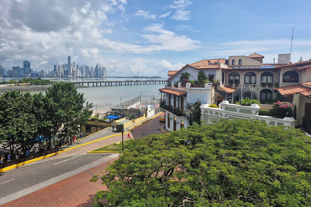 Un paisaje urbano costero con un puente destacado, edificios históricos y un paseo marítimo.