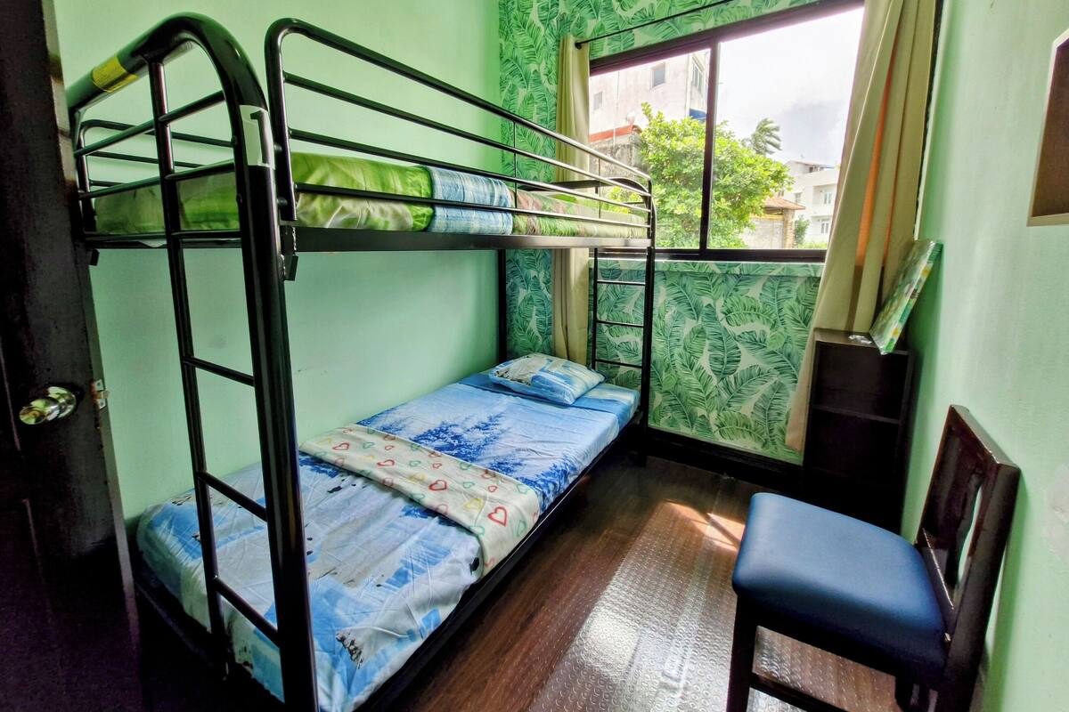 Dormitorio con literas, una ventana, un escritorio y una silla.