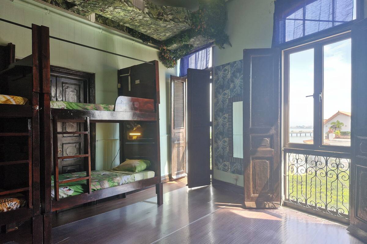 Una habitación con una cama litera, una mesita pequeña y una ventana que da a vistas del exterior.
