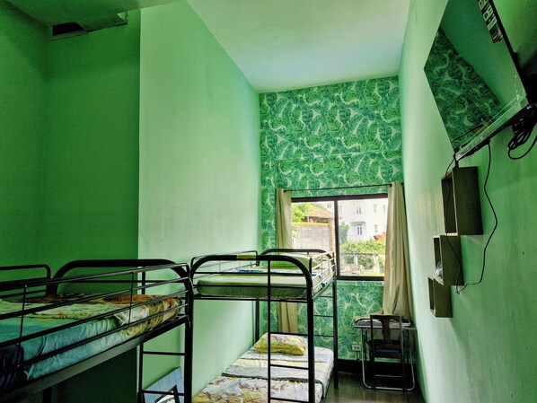 Un dormitorio con literas, una ventana con vistas y una pared con diseño verde.