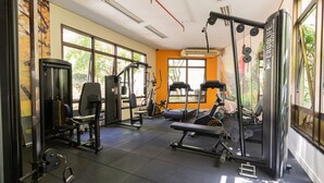 A gym with exercise equipment, large windows, and an air conditioning unit. - Elegance Suítes Vila Olímpia (Sao Paulo)