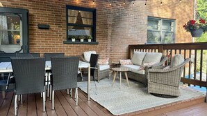 An outdoor patio with wicker furniture, a brick wall, and string lights.
