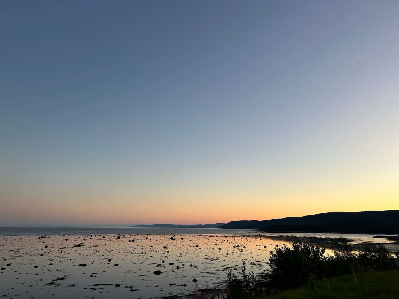 Una playa con rocas dispersas y un cielo despejado.