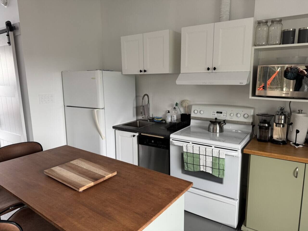 A compact kitchen with white cabinets, a stove, a dishwasher, and a refrigerator.