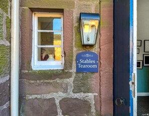 A stone building with a window, a door, and a sign reading 'Stables Tearoom.' - South Lodge - UK48318 (Berwick-Upon-Tweed)