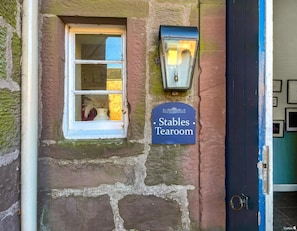 A stone building with a window, a door, and a sign reading 'Stables Tearoom.' - South Lodge - UK48318 (Berwick-Upon-Tweed)