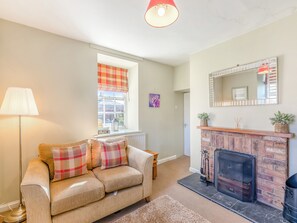 Un salón con sofá, chimenea, ventana con vistas y una lámpara.