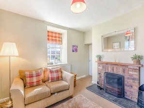 A living room with a sofa, a fireplace, a window with a view, and a lamp. - South Lodge - UK48318 (Berwick-Upon-Tweed)