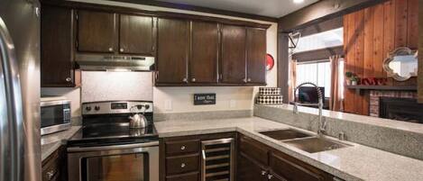 A modern kitchen with stainless steel appliances, wooden cabinets, and a granite countertop.