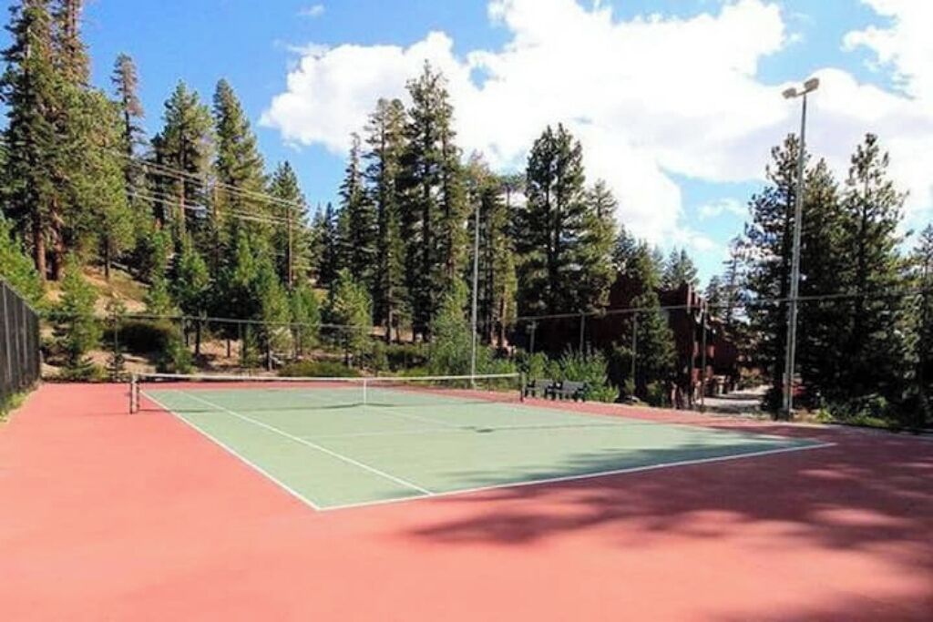 An outdoor tennis court surrounded by trees.