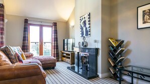 A living room with a sofa, a fireplace, a television, and a bookshelf. - Beautiful 3-Bed Riverside Townhouse with Parking - Pass the Keys (Belfast)