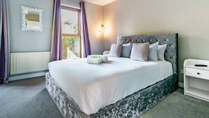A bedroom with a large bed, a bedside table, a nightstand, a mirror, and a window with curtains. - Beautiful 3-Bed Riverside Townhouse with Parking - Pass the Keys (Belfast)