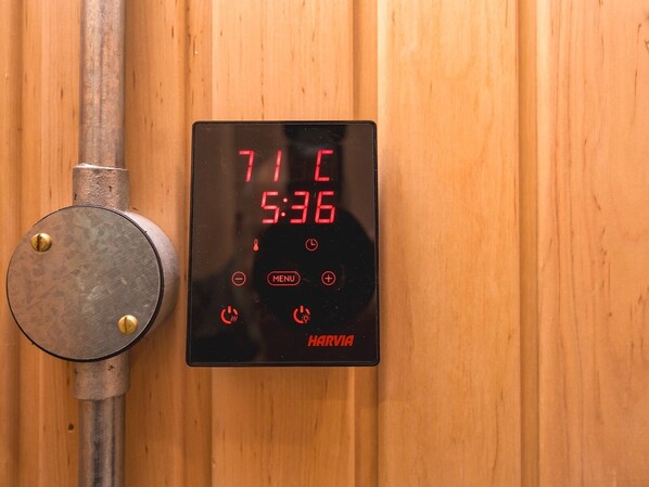 A digital thermostat with a wooden wall background, displaying a temperature of 71 degrees and a time of 5:36.