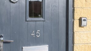 Harmaa ovi, jossa on numero 45, ikkuna, ovikello ja postilaatikko.
