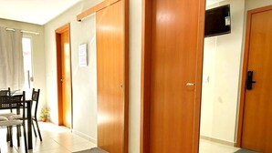 Une chambre d’hôtel avec des portes en bois, un coin repas avec une table et des chaises, et un téléviseur fixé au mur.
