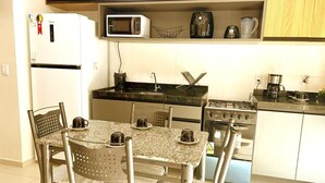 Une cuisine compacte équipée d’un réfrigérateur, d’un four à micro-ondes, d’une machine à café et d’une cuisinière.