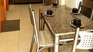 Un espace de vie compact comprenant une table à manger, des chaises, un canapé, un téléviseur et un réfrigérateur.