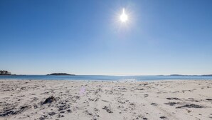 Platja amb empremtes a la sorra i un cel blau clar.