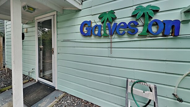 A building with a sign that reads "Graveson" and two palm tree decorations.