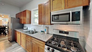 A modern kitchen with wooden cabinets, stainless steel appliances, and a granite countertop.